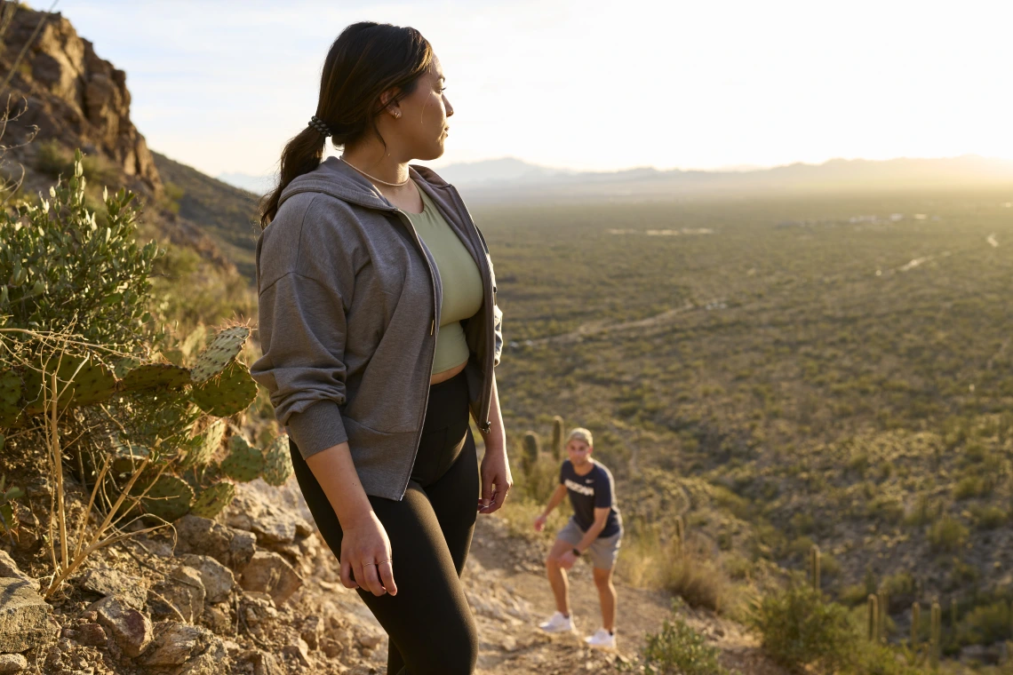 female student hiking in desert, looking into sunset